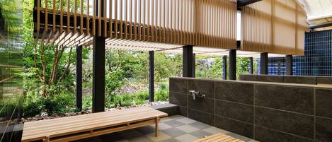 A modern outdoor seating area with wooden benches, a stone wall, and a view of greenery.