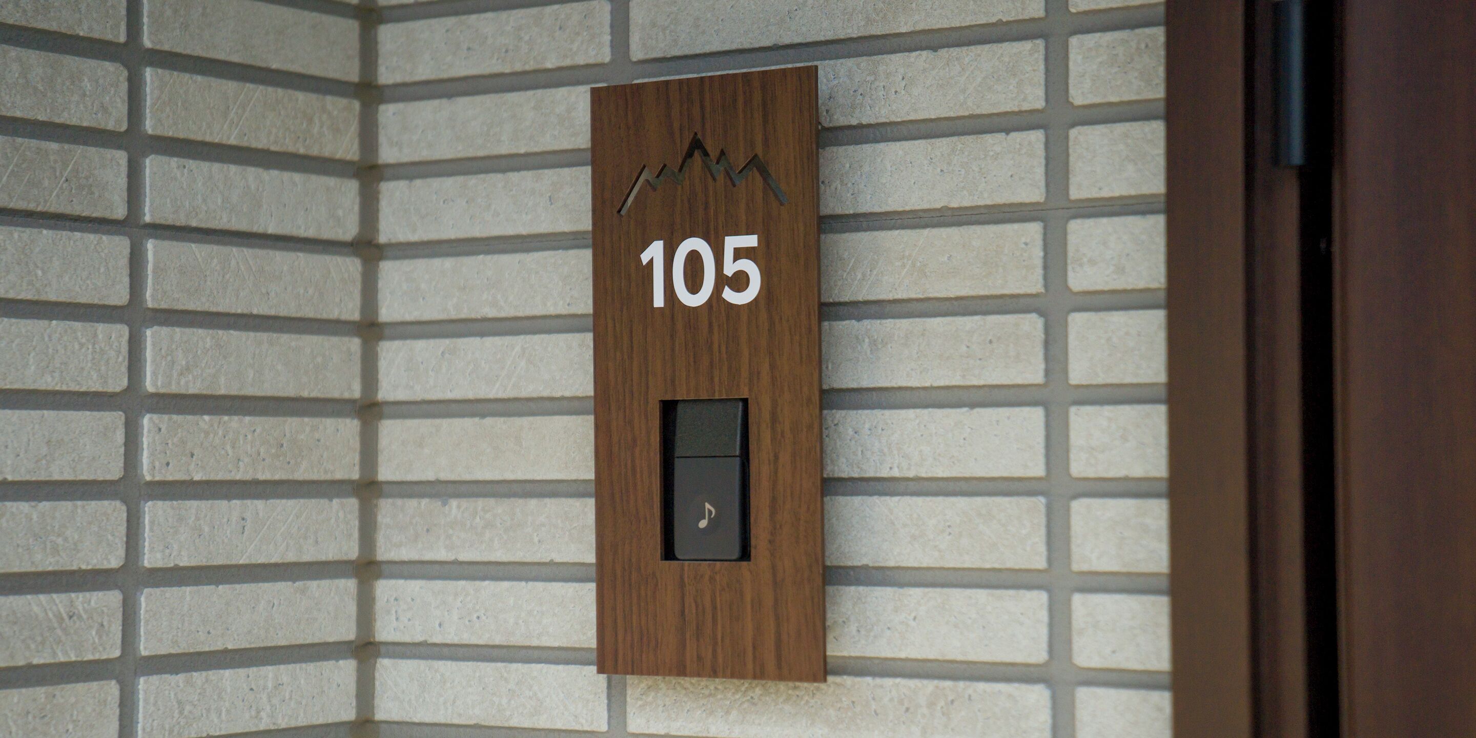 Een houten paneel met het nummer 105, dat een kamer of locatie aangeeft.