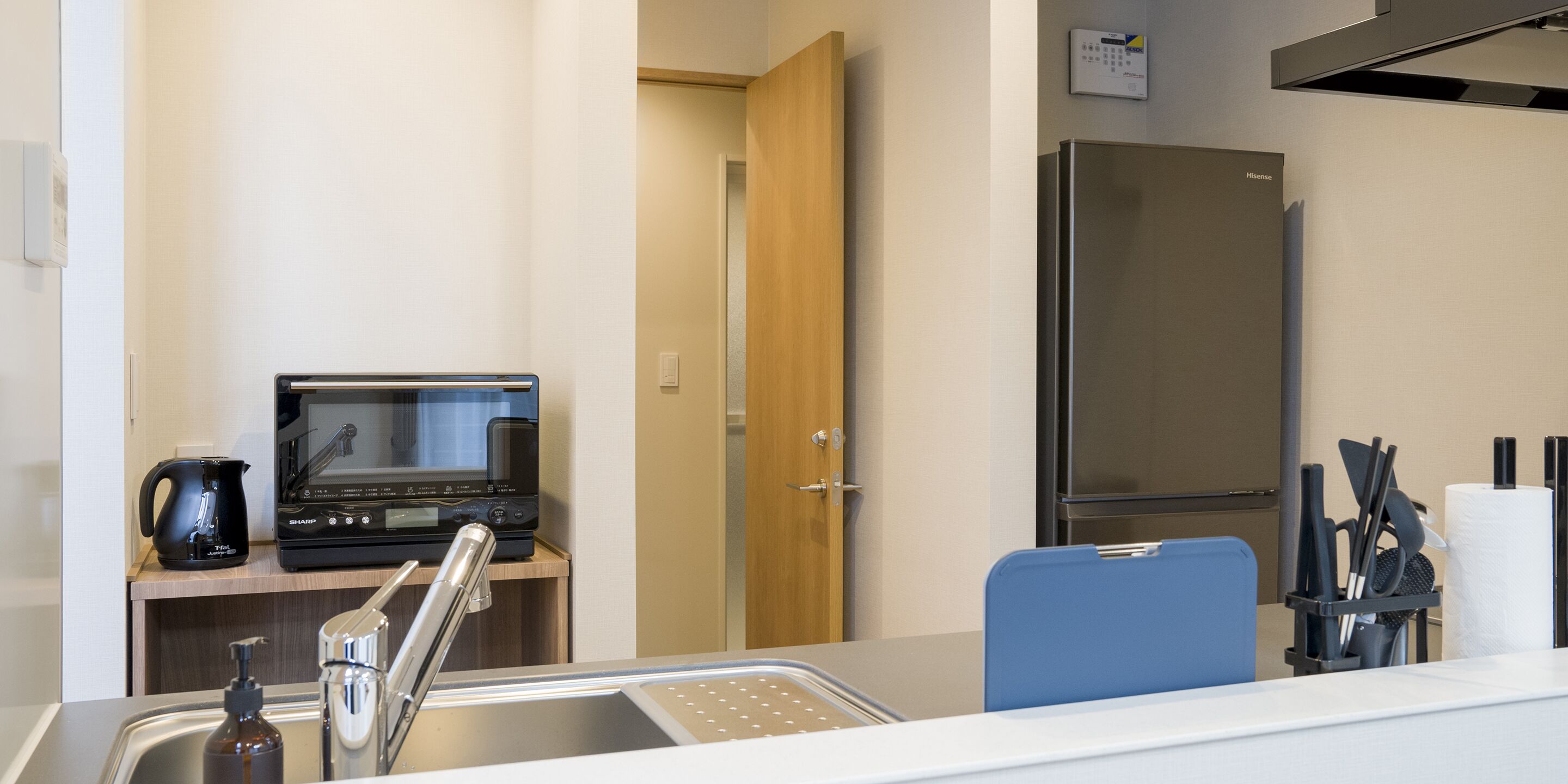 A modern kitchenette with a microwave, coffee maker, and a refrigerator.