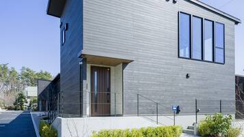 A modern two-story building with a grey facade, large windows, and a visible entrance.