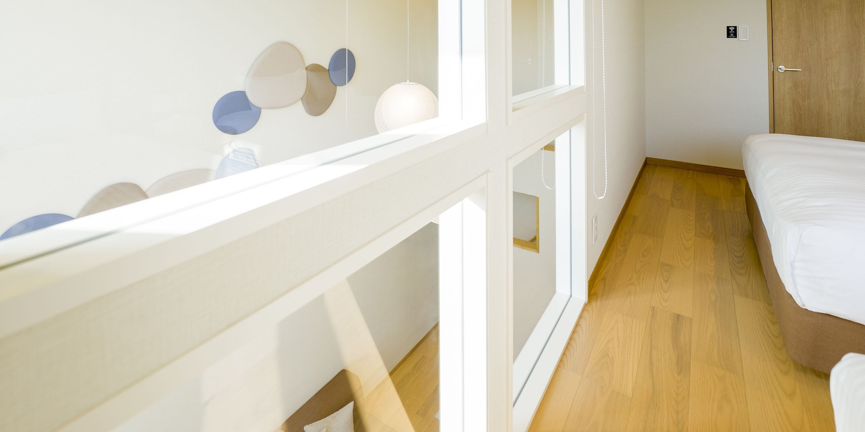 Una habitación de hotel con piso de madera, una cama, pared blanca y una puerta.