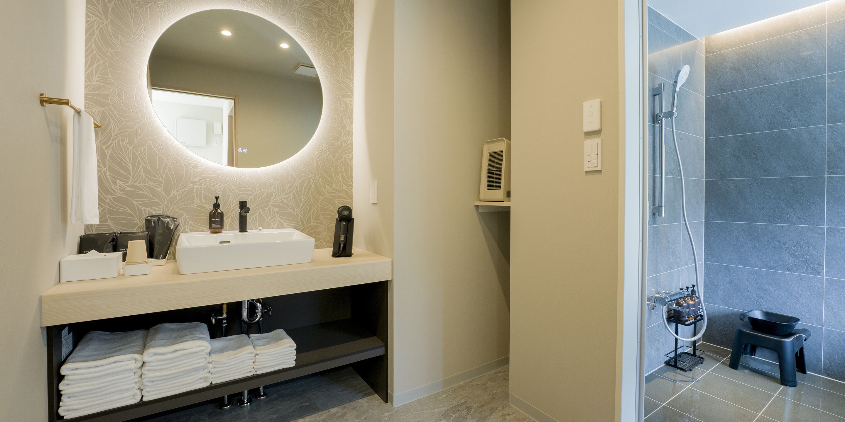 A modern bathroom with a round mirror, a sink, and a shower area.