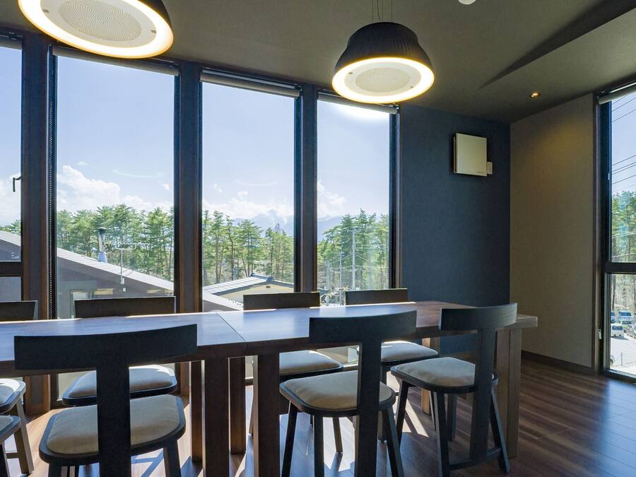 Un espace repas moderne doté de grandes fenêtres, de tables en bois et de chaises.