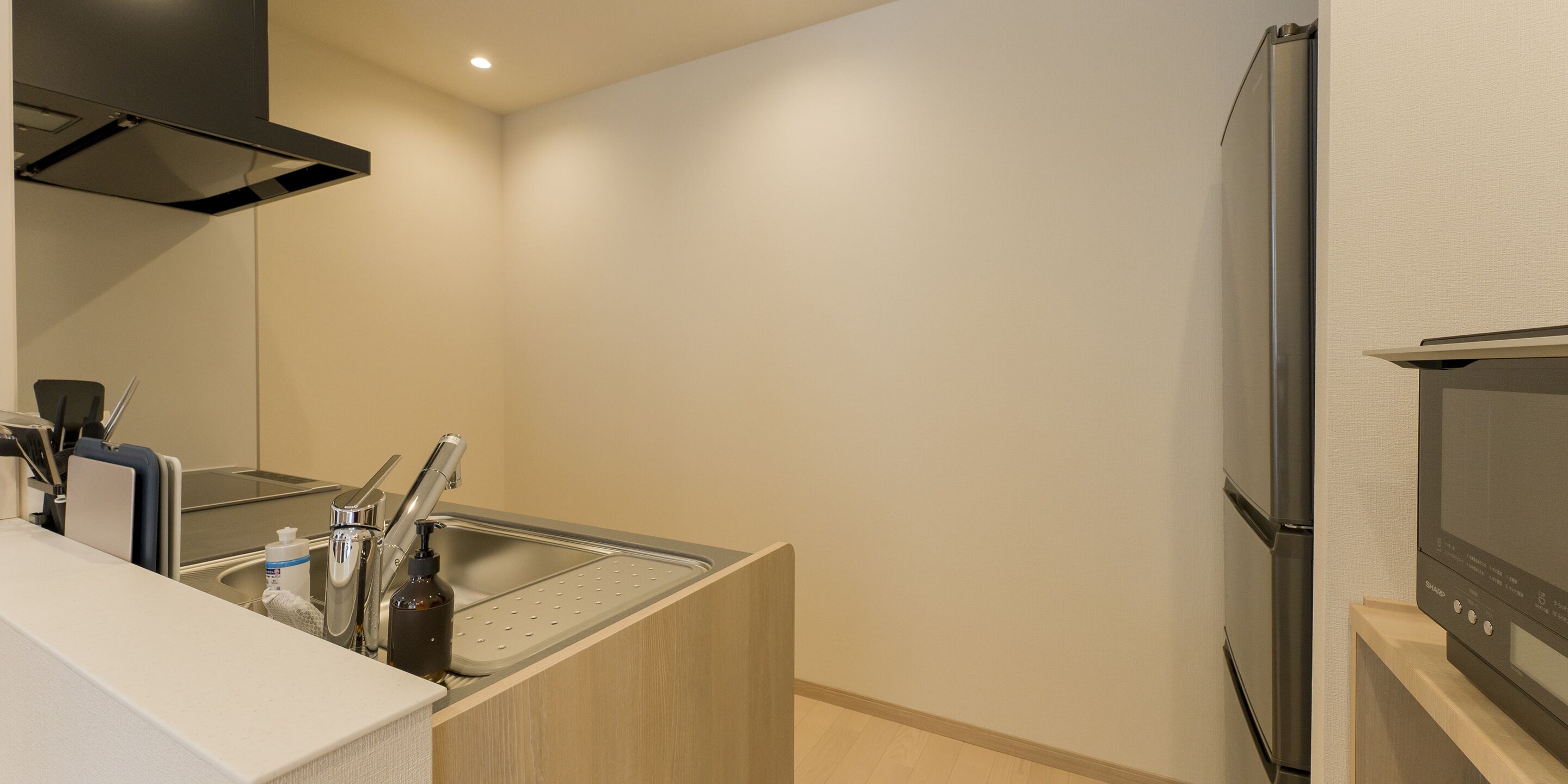 A modern kitchen with a built-in oven, a stainless steel sink, and a compact refrigerator.