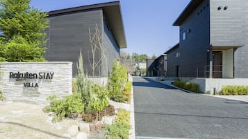 A modern building with a stone sign reading "Rakuten Stay Villa" and a well-maintained garden area.