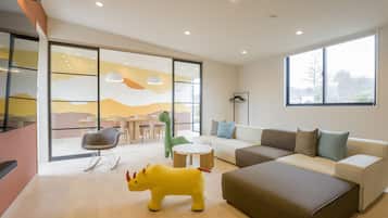 A modern living room with a sofa, a dining area, and a large window.