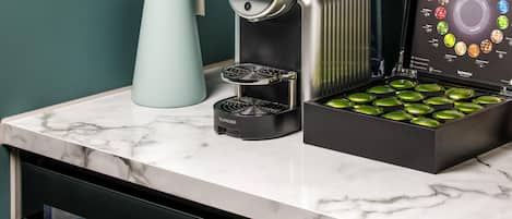 A kitchen with a coffee machine, a kettle, and a box of coffee pods.