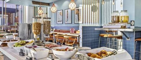 Uma mesa de buffet com diversos alimentos e uma área de estar num restaurante moderno.