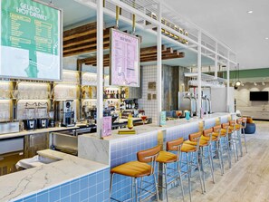 A bar area with a menu board, bar stools, and a counter with bar equipment. - Ibis Styles Paignton (Paignton)