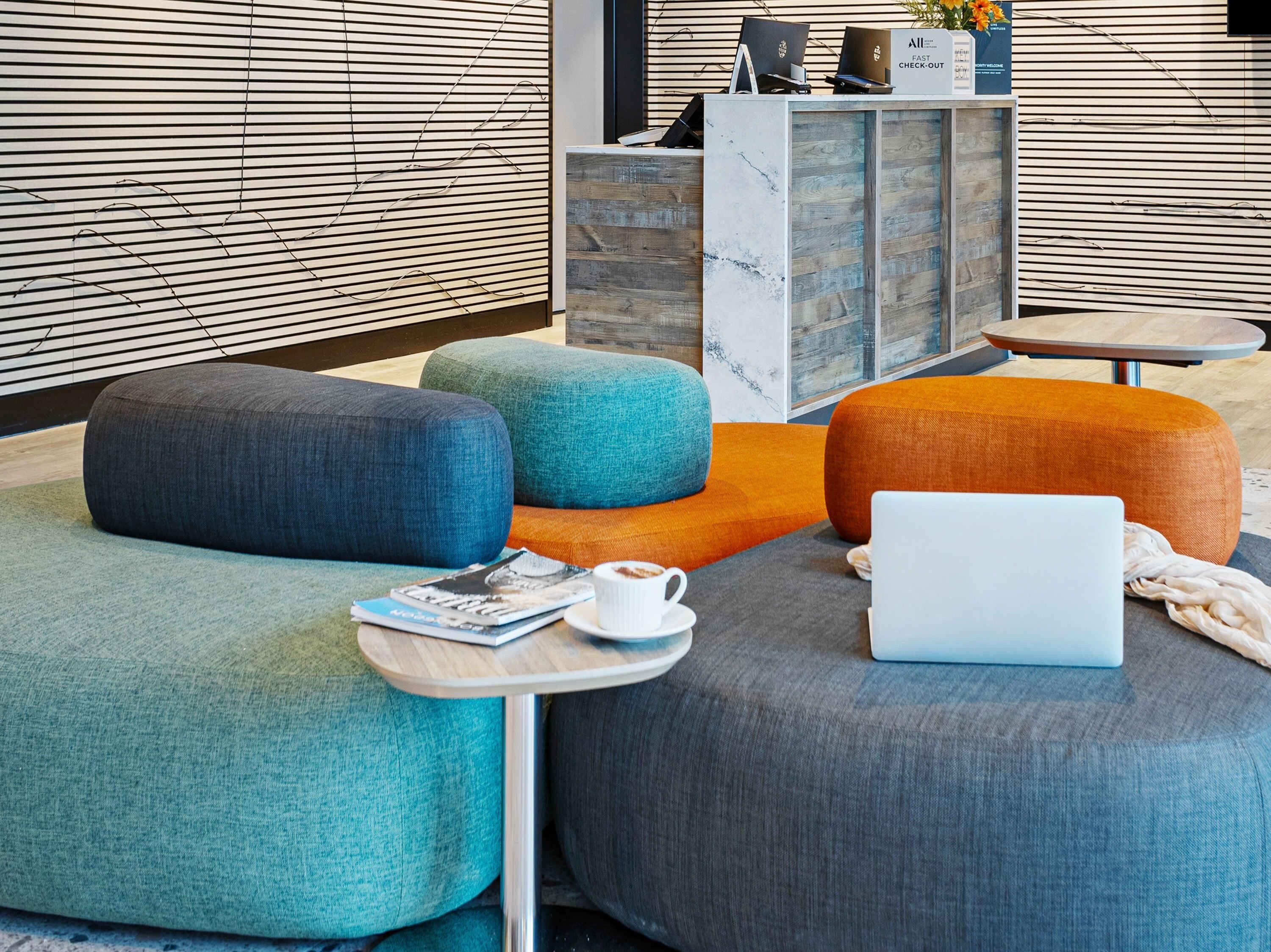 A modern lounge area with colorful, rounded seating and a laptop on a table.