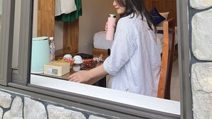 Una persona con una camisa a rayas de pie junto a un mostrador, con una botella de agua, una caja y una taza.