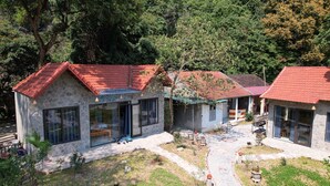 Un edificio de piedra con techo rojo, ventanas grandes y un camino de piedra que lleva a la entrada.