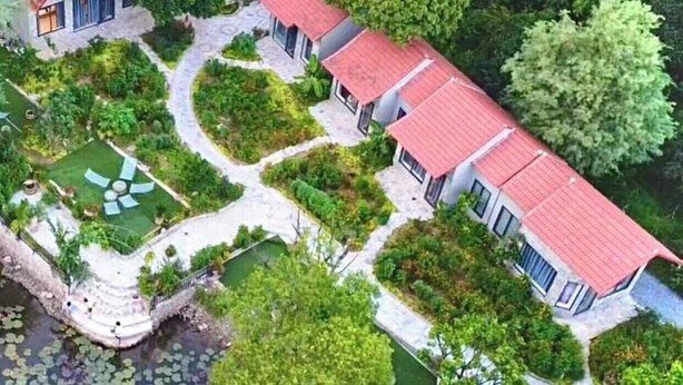 Zona residencial con varias casas, un jardín central y un estanque con nenúfares.