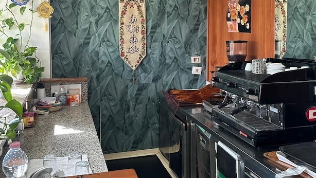 A kitchen with a coffee machine, a wooden counter, and decorative wall panels. - Residence Politecnico Bovisa (Milan)