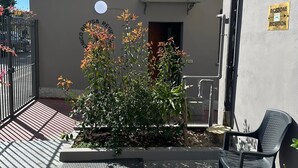 A building with a reception sign, a gated entrance, and a small garden area with a bench and chair. - Residence Politecnico Bovisa (Milan)
