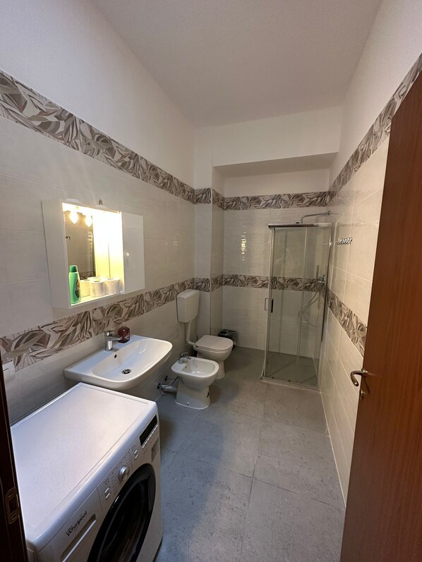 A bathroom with a sink, toilet, bidet, and a glass-enclosed shower. - Residence Politecnico Bovisa (Milan)