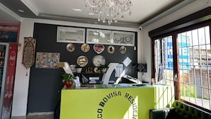 A reception area with a green counter, a chandelier, and a window with a view of the outside. - Residence Politecnico Bovisa (Milan)