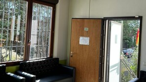 A room with a chandelier, a wooden door, and a seating area with a sofa and armchairs. - Residence Politecnico Bovisa (Milan)