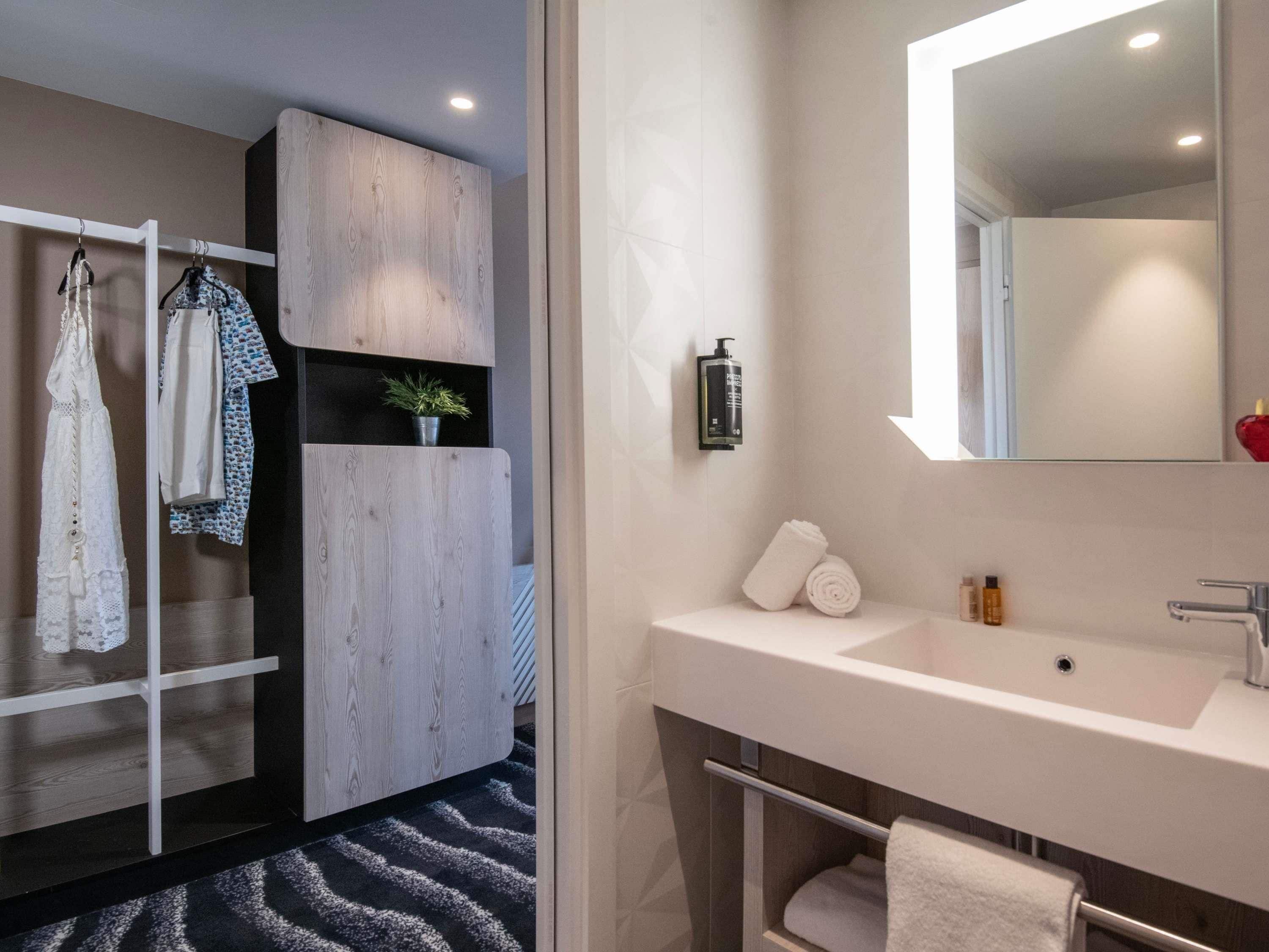 Un baño moderno con un espejo grande, lavamanos blanco y toallero.
