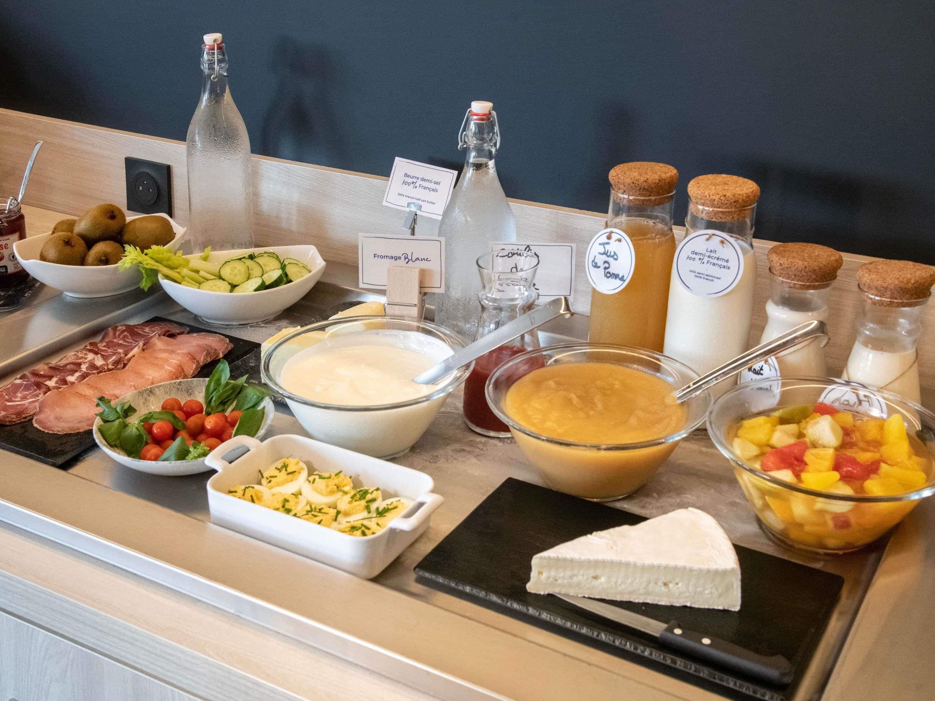 A buffet with various food items including meats, cheeses, and fruits.