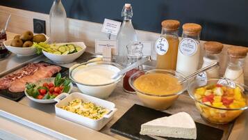 A buffet with various food items including meats, cheeses, and fruits.