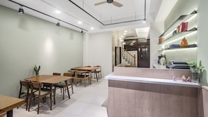 A modern interior with a dining area, a reception desk, and a staircase leading to another level. - Spring Rain Hostel (Meishan)