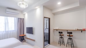 A modern hotel room with a large bed, a TV, a desk with two chairs, and a chandelier. - Spring Rain Hostel (Meishan)