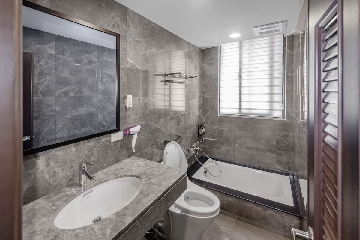A modern bathroom with a marble sink, a toilet, and a bathtub.