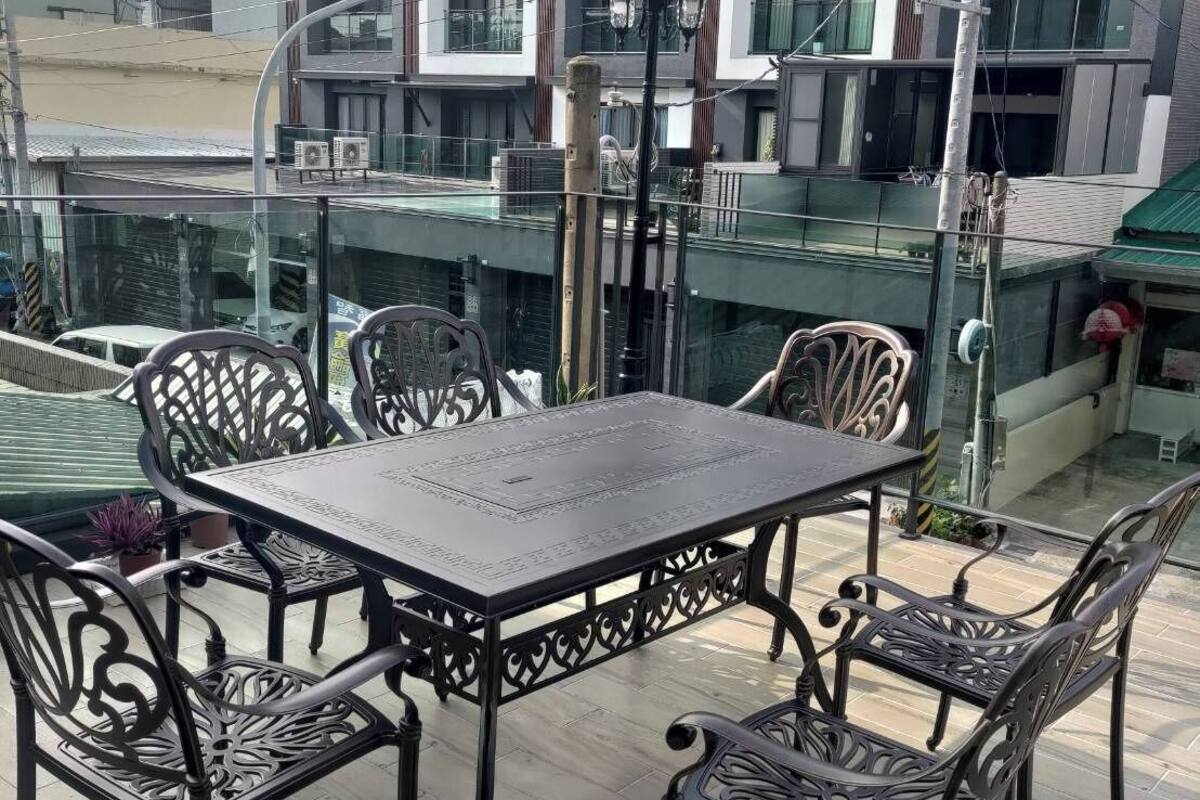A rooftop terrace with a table and chairs, surrounded by a glass balustrade.