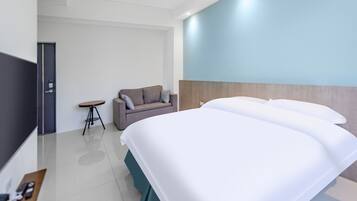 A modern hotel room with a large bed, a small sofa, a side table, and a TV.