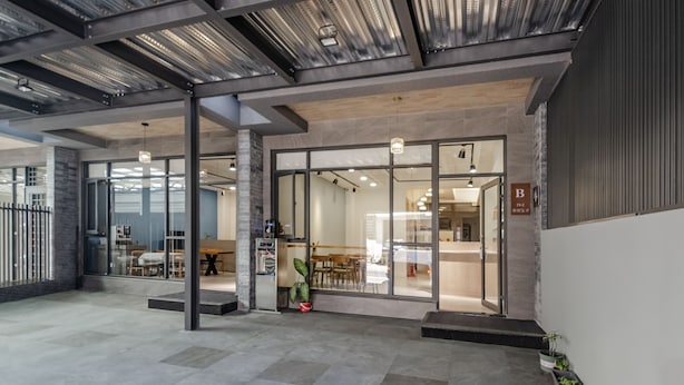 An interior space with a modern design, featuring a glass entrance, a seating area with tables, and a visible sign indicating room B. - Spring Rain Hostel (Meishan)