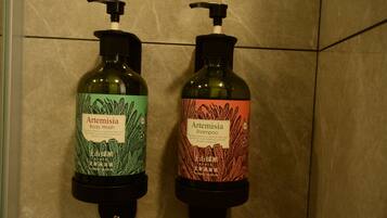 Two bottles of Artemisia body wash and shampoo on a tiled wall.
