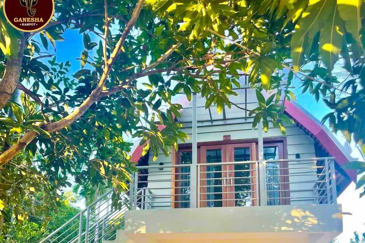 Um edifício de dois andares com varanda, escada e baloiço.