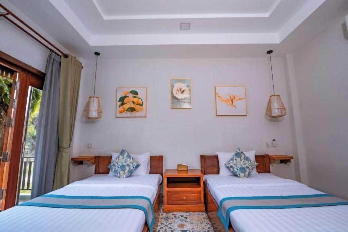 A bedroom with two beds, a ceiling light, and wall-mounted artwork.