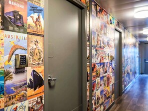 Un pasillo con carteles de viajes en las paredes y una puerta con cerradura electrónica.