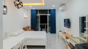 Een moderne hotelkamer met een bed, nachtkastjes, een televisie en een balkon met blauwe gordijnen.