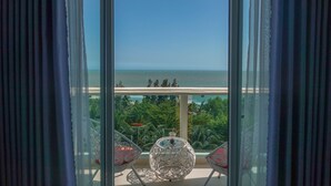Een balkon met helder uitzicht op zee, een drankje op een tafeltje en twee stoelen.