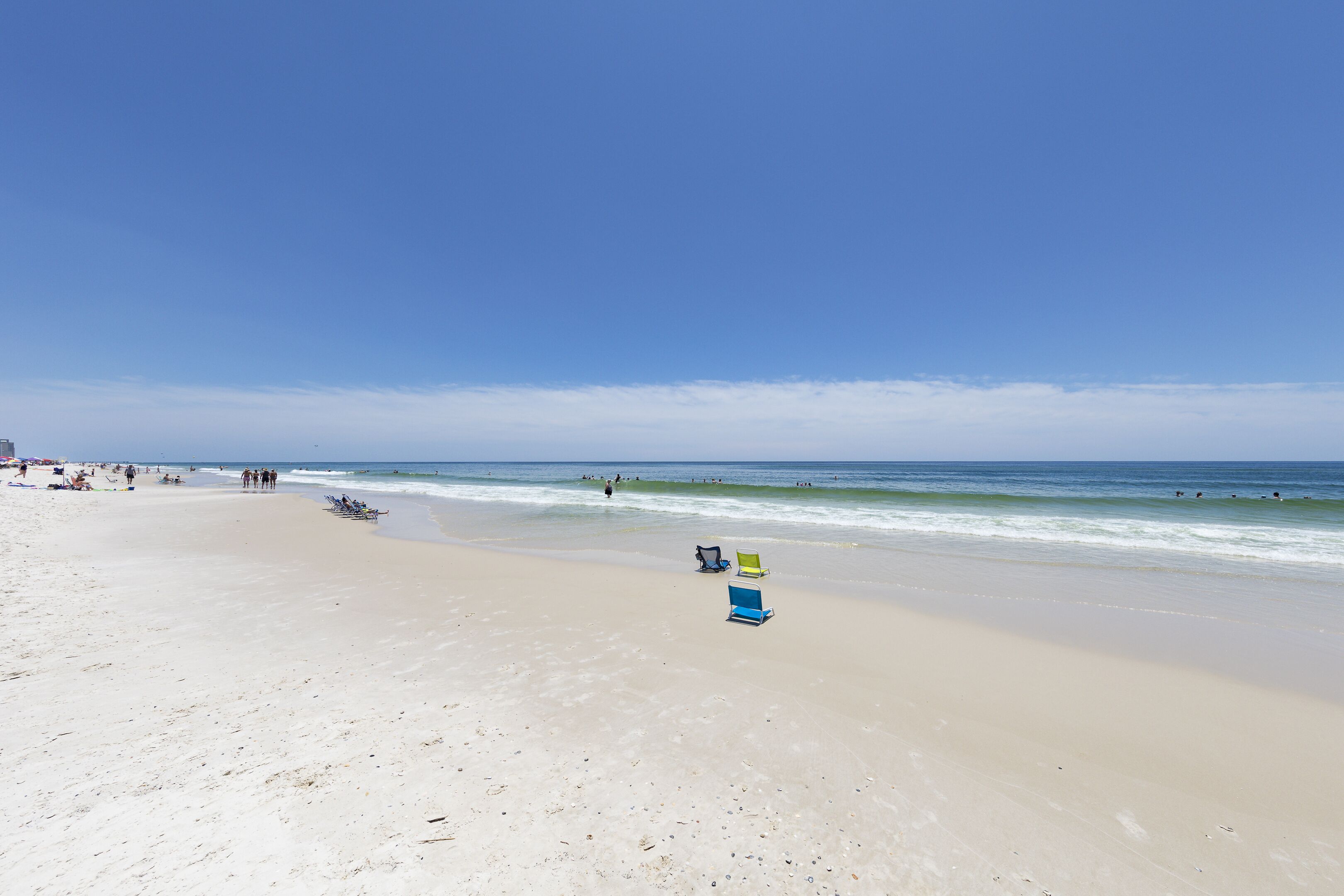 A wide sandy beach with a clear blue sky.