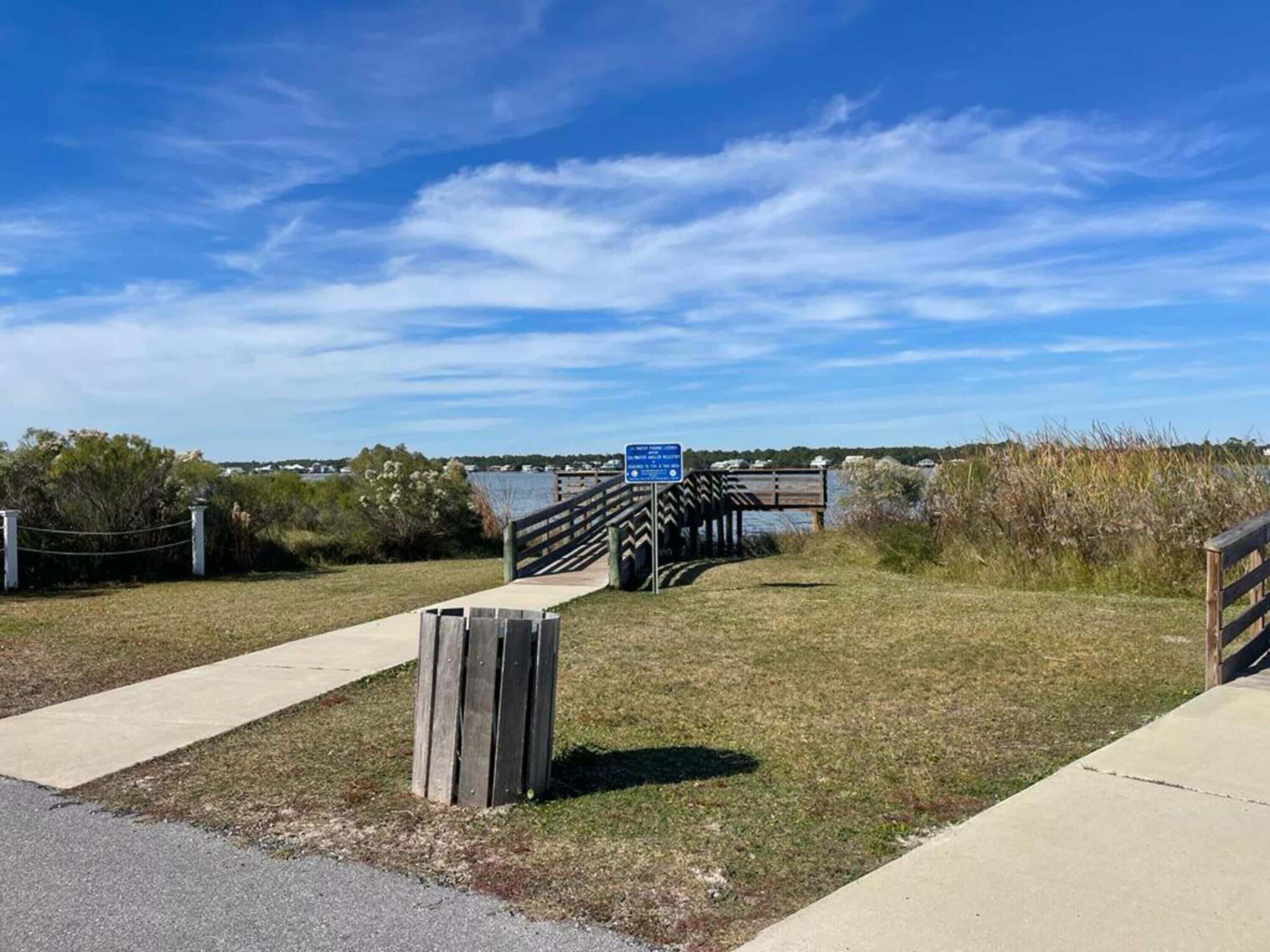 A wooden boardwalk leading to a pier with a blue informational sign.