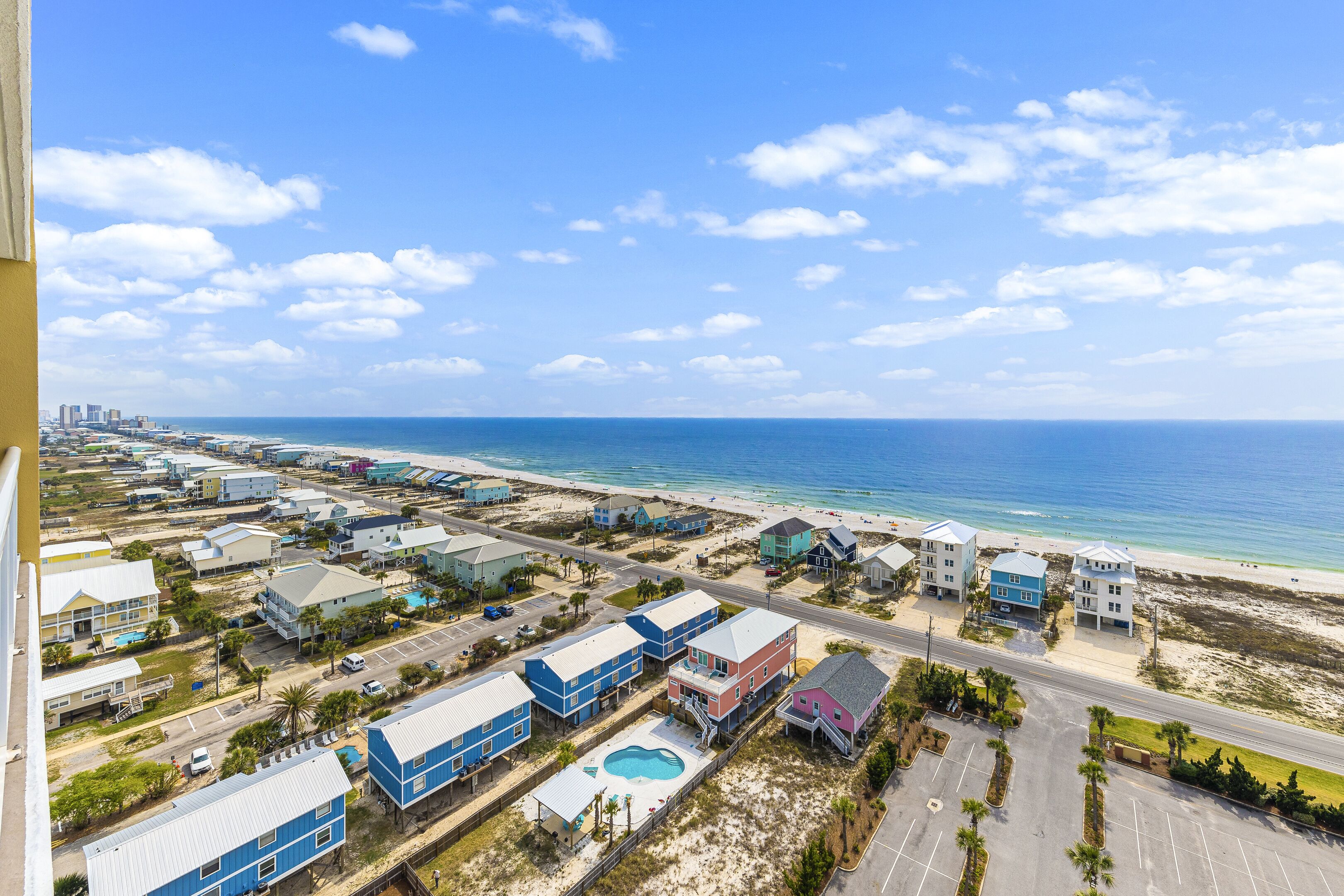 An aerial view of a coastal residential area with houses, a beach, and a clear sky.