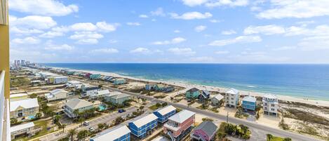 An aerial view of a coastal residential area with houses, a beach, and a clear sky.