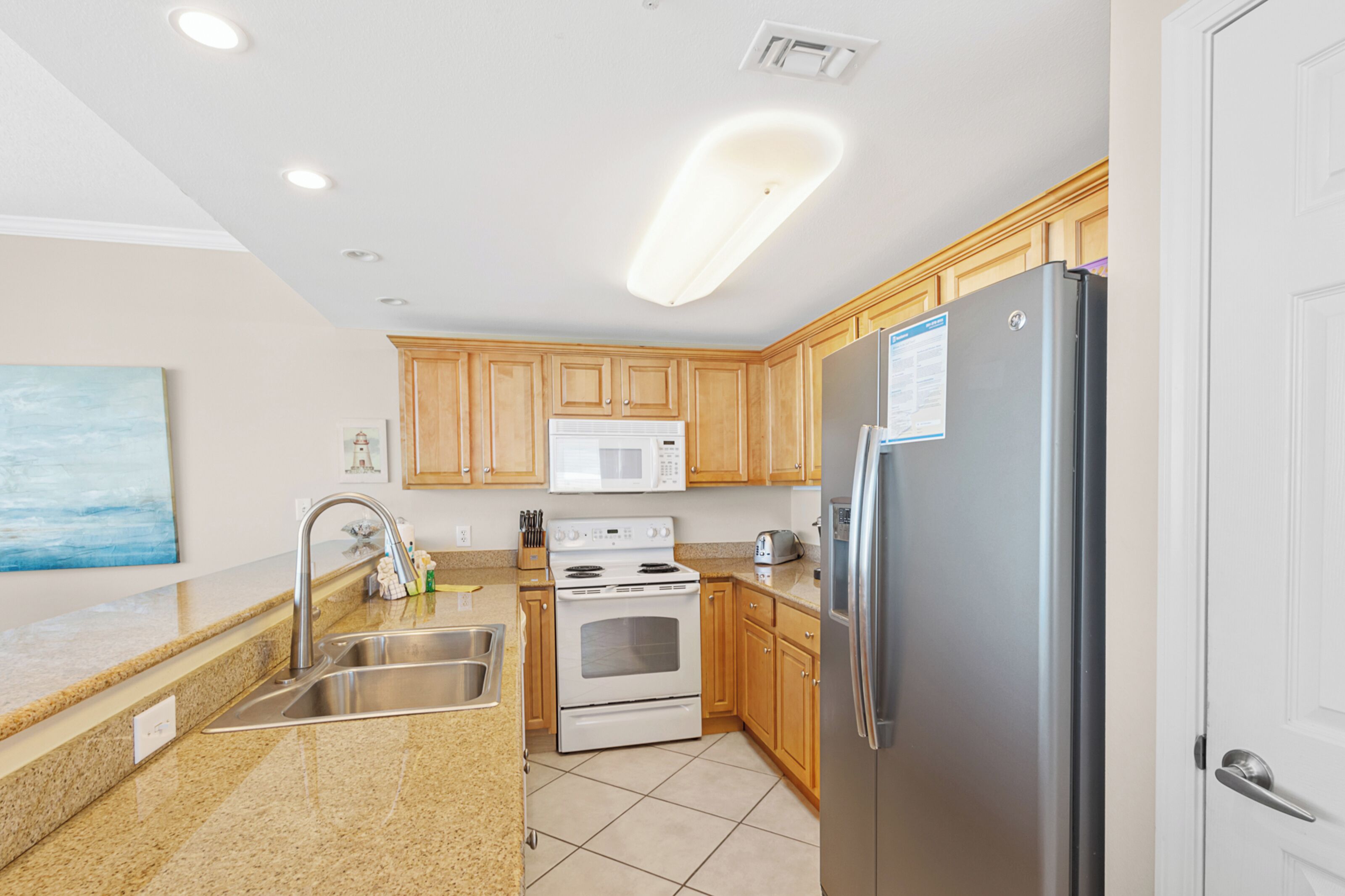 A modern kitchen with granite countertops, stainless steel appliances, wooden cabinets, and a microwave.
