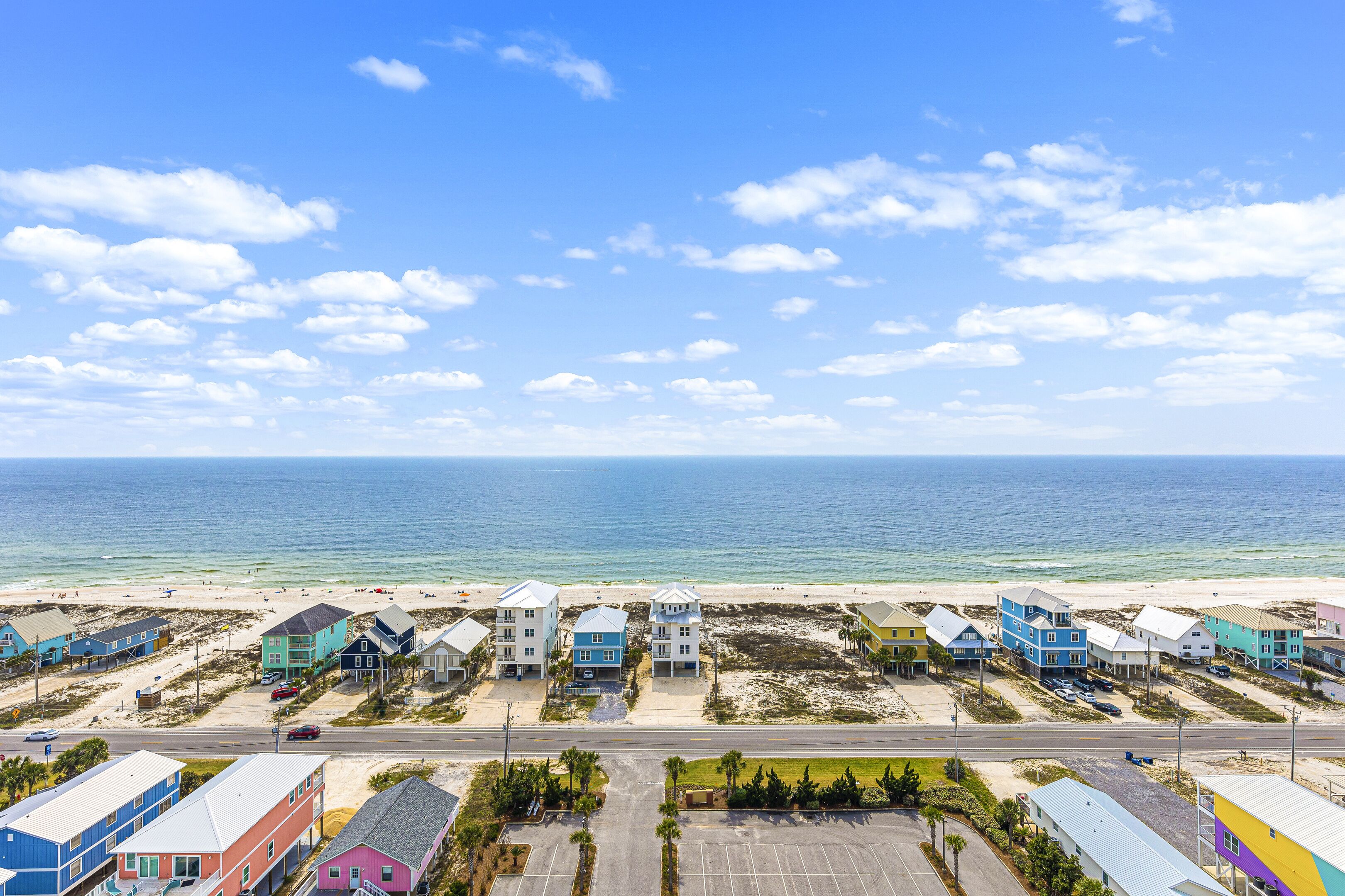 A coastal residential area with colorful houses, a beach, and a clear sky.