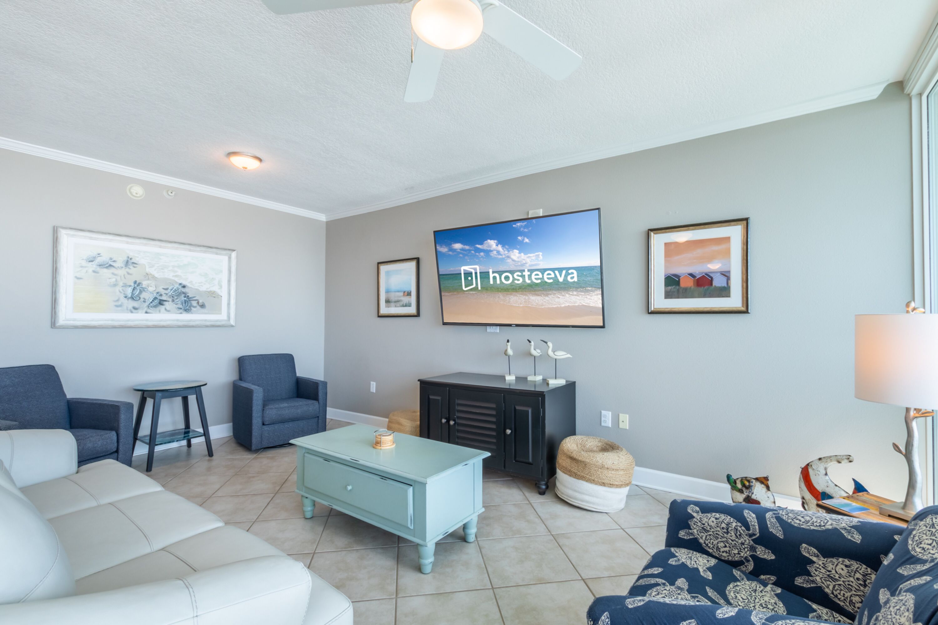 A living room with a television, two sofas, a coffee table, and a ceiling fan.