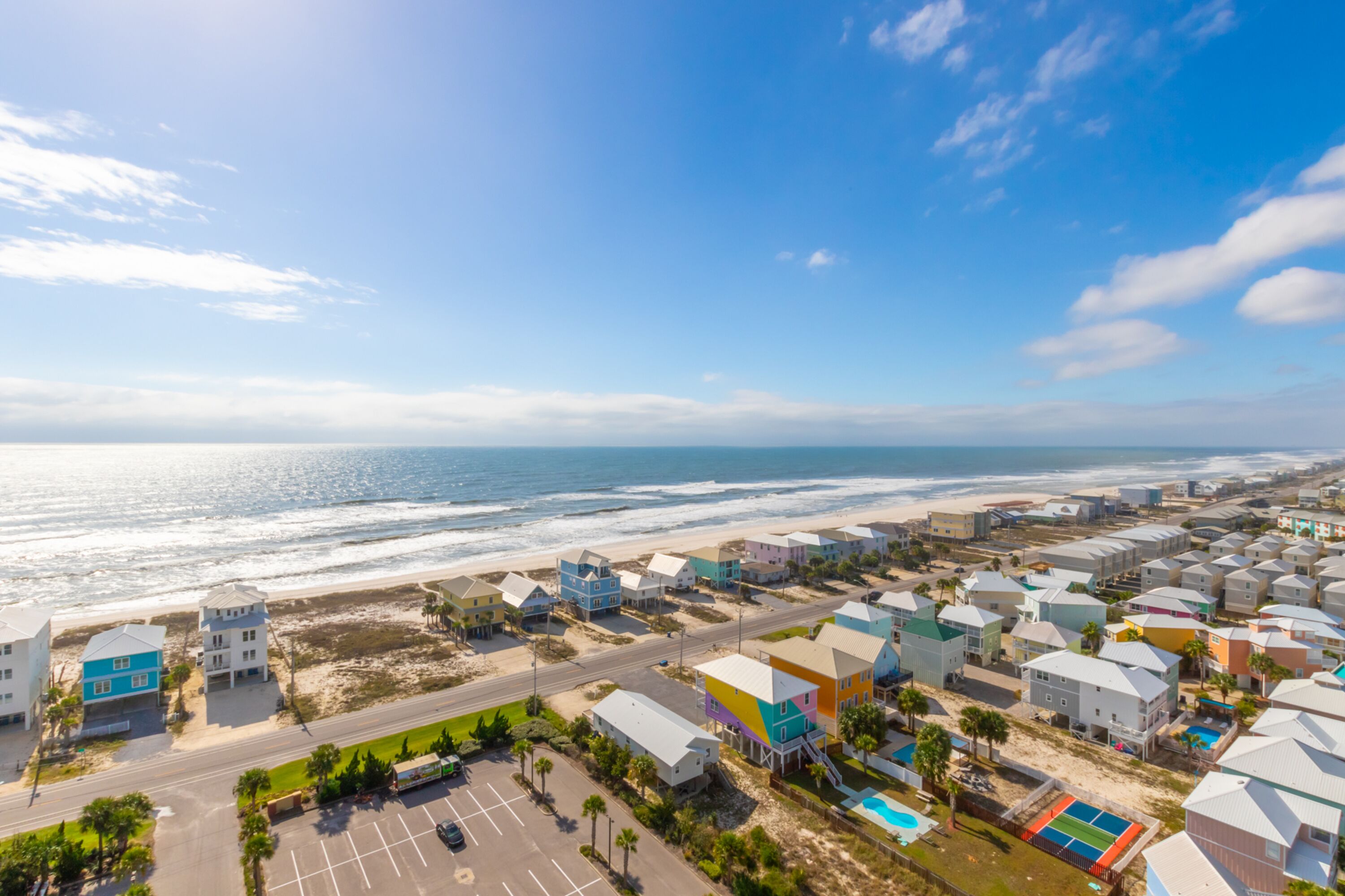 A coastal residential area with colorful houses, a beach, and a clear sky.