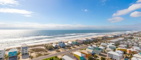 A coastal residential area with colorful houses, a beach, and a clear sky.