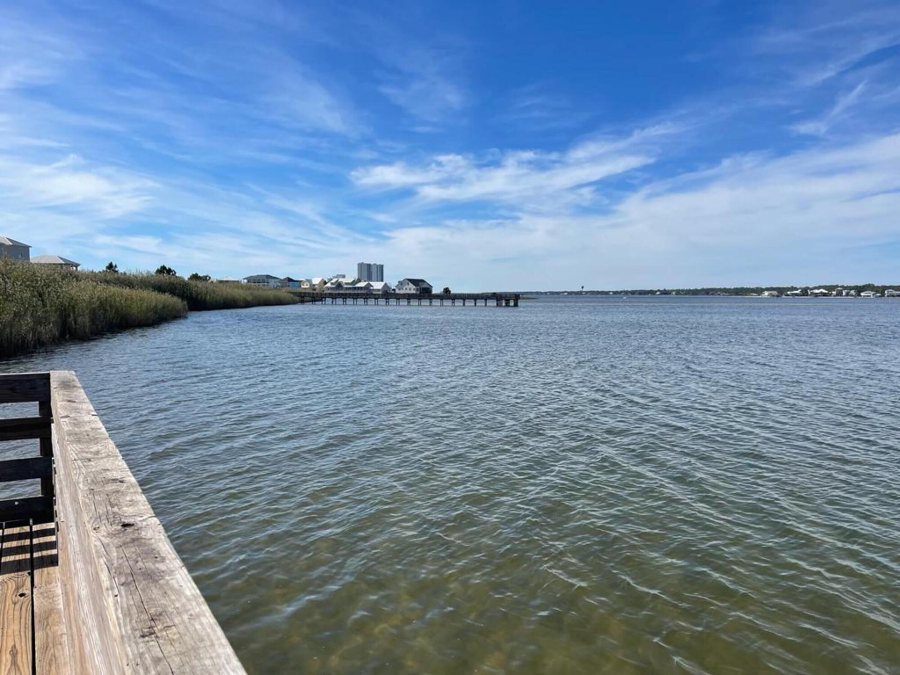 A wooden pier extending into calm waters with a clear sky above.