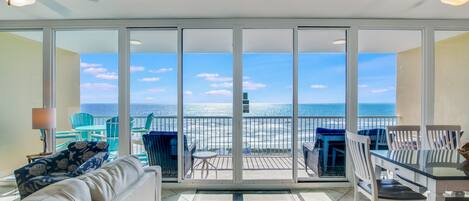 A balcony with a view of the ocean, furnished with a sofa, chairs, and a table.