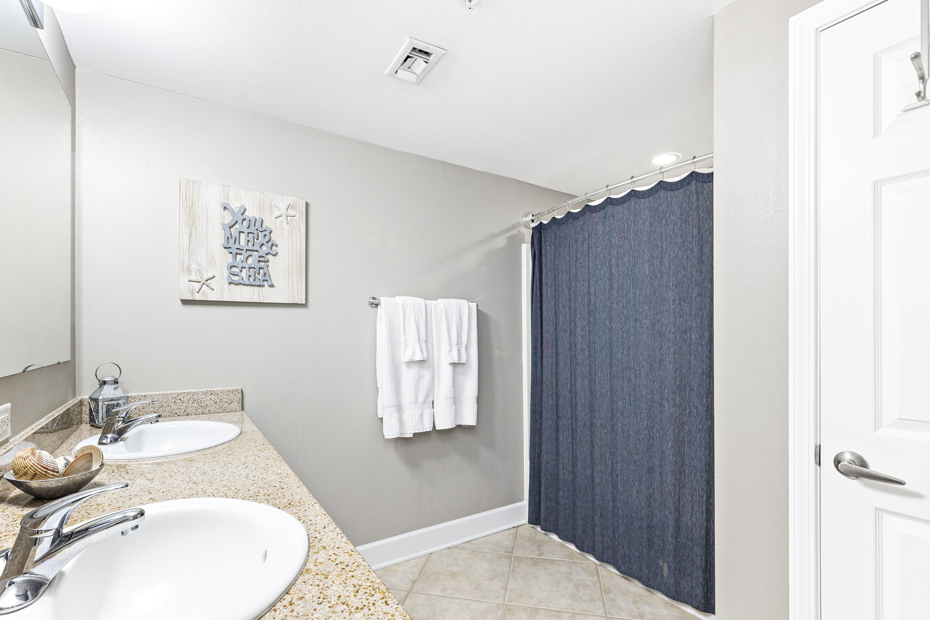 A bathroom with two sinks, a shower curtain, and a towel rack.