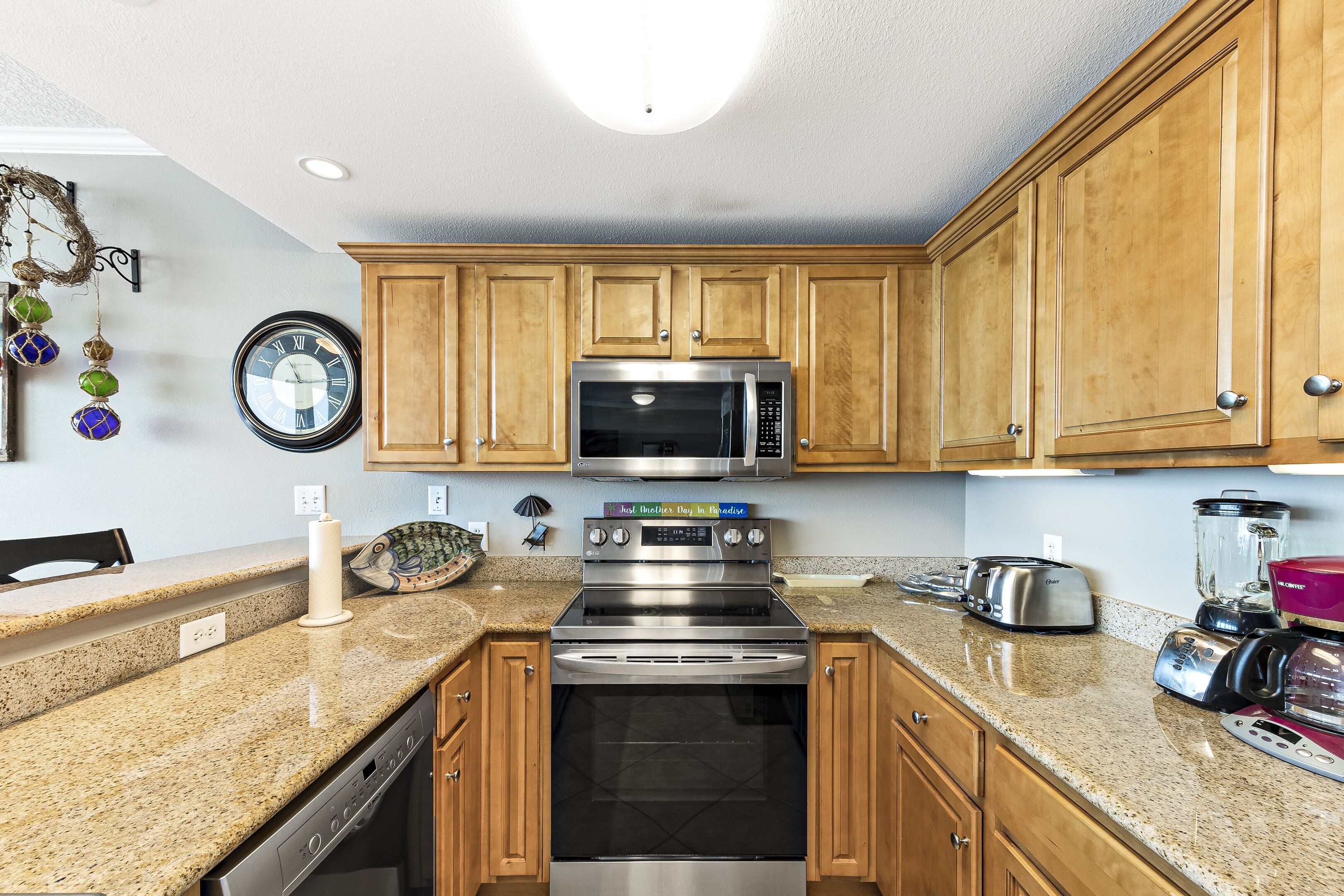 A kitchen with wooden cabinets, a stainless steel microwave, an oven, a toaster, and a blender.